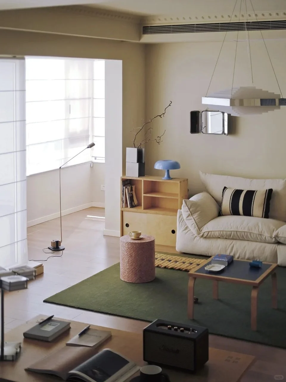 Cream sofa, olive green rug and a low wood coffee table in a compact living room with a blue table lamp.