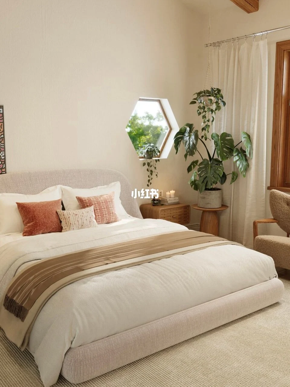Cream upholstered bed with rust cushions, a tan throw, wood bedside furniture and green plants beside a small hexagonal window.