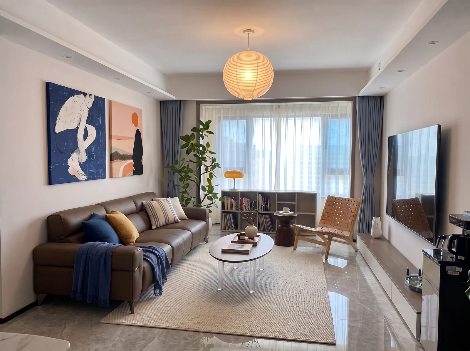 Proposed softer living room concept with brown leather sofa, cream rug, oval wood table, woven wood chair, blue artwork and paper pendant around gray tile.