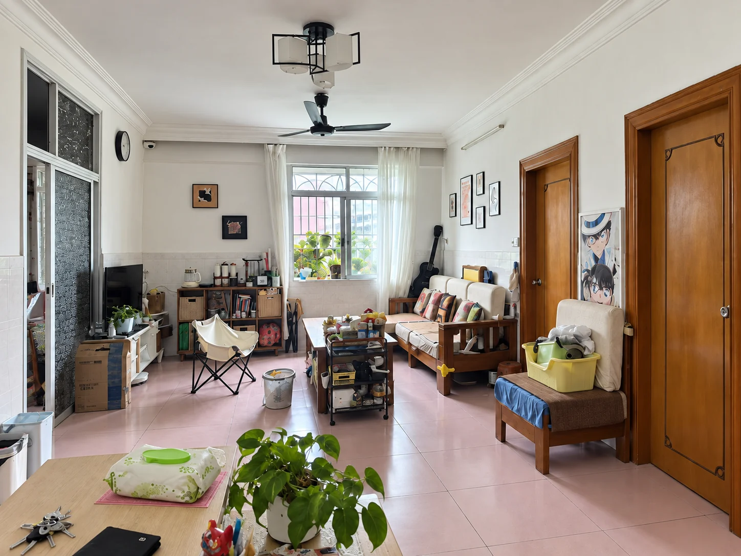 Original living room with pink tile floor, half-height white wall tile, wood doors and mixed furniture.